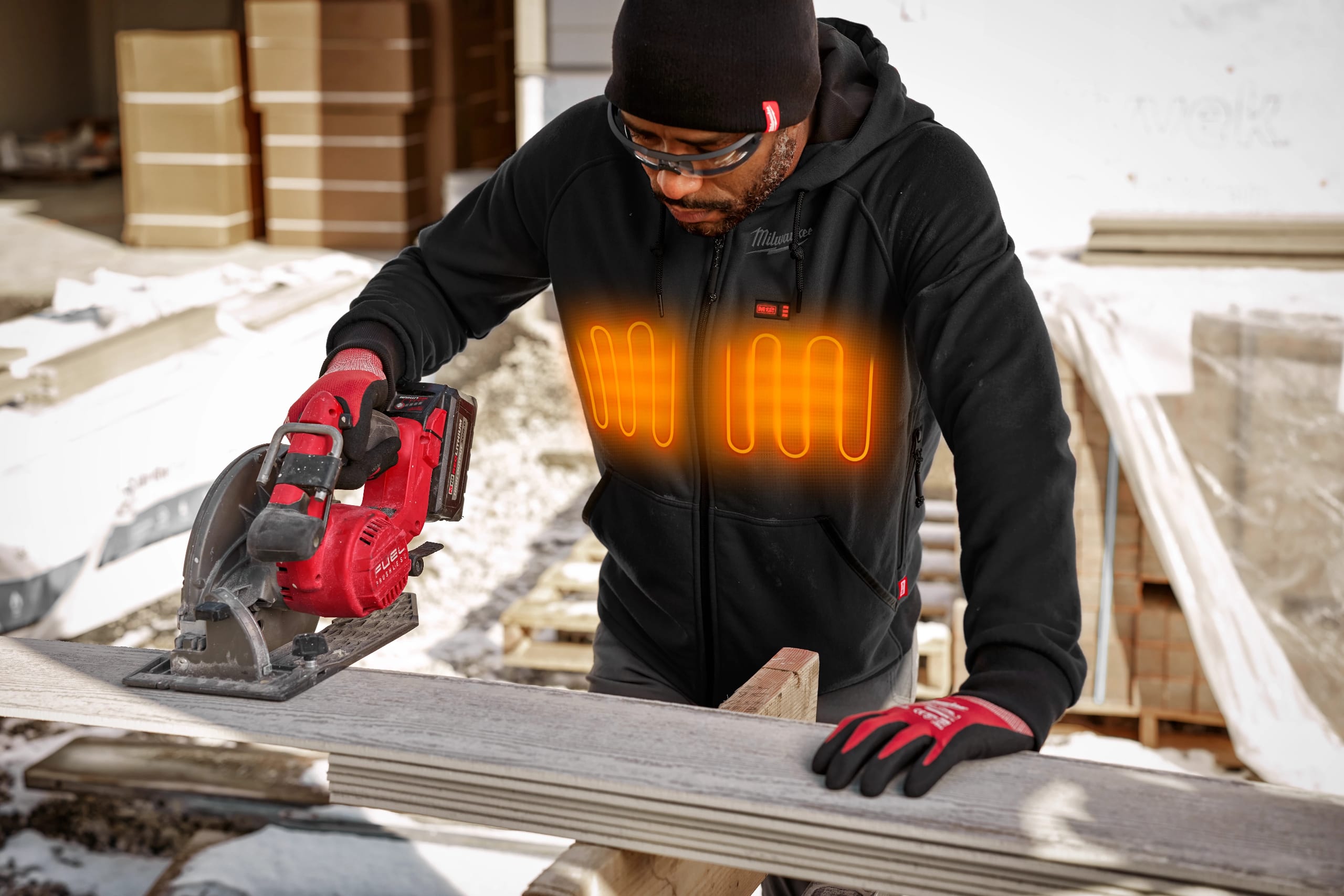 Man wearing Milwaukee Heated Gear using a circular saw